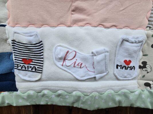 liebevoll arrangiere ich die Erstlingsausstattung auf die Erinnerungsdecke, wenn sie zu klein ist, um ausgeschnitten zu werden