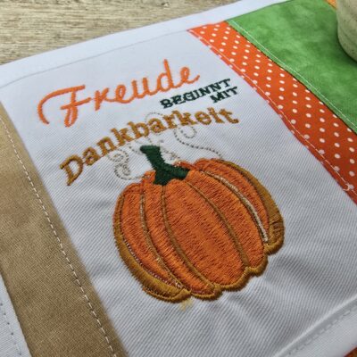 Tassenuntersetzer in Patchworkarbeit, bestickt mit Kürbis zur Herbstzeit. Mitbringsel und Geschenkidee zur herbstlichen Tischdekoration