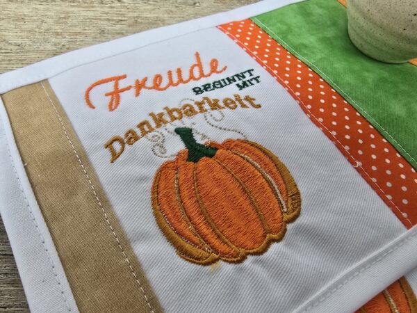 Tassenuntersetzer in Patchworkarbeit, bestickt mit Kürbis zur Herbstzeit. Mitbringsel und Geschenkidee zur herbstlichen Tischdekoration