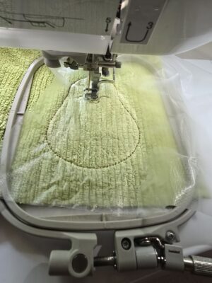 aus alten Handtücher werden wiederverwendbare und waschbare Kosmetikpads. Hier eine Avocado aus einem grünen Handtuch im Stickprozess