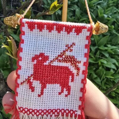 Handgesticktes Osterfähnchen mit IHS und Osterlamm. Doppelseitig bestickt, mit feinen Goldakzenten. Traditionelle, ruhige Handarbeit – ideal für Osterlammkuchen und Osterdeko.