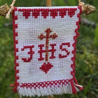 Handgesticktes Osterfähnchen mit IHS und Osterlamm. Doppelseitig bestickt, mit feinen Goldakzenten. Traditionelle, ruhige Handarbeit – ideal für Osterlammkuchen und Osterdeko.