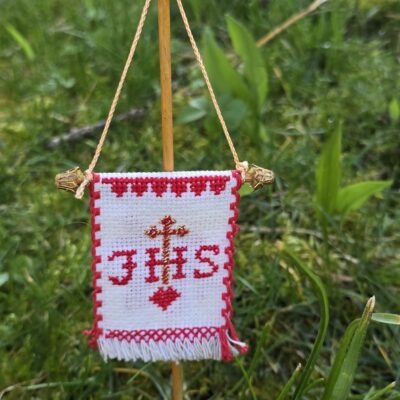 Handgesticktes Osterfähnchen mit IHS und Osterlamm. Doppelseitig bestickt, mit feinen Goldakzenten. Traditionelle, ruhige Handarbeit – ideal für Osterlammkuchen und Osterdeko.