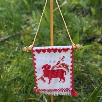 Handgesticktes Osterfähnchen mit IHS und Osterlamm. Doppelseitig bestickt, mit feinen Goldakzenten. Traditionelle, ruhige Handarbeit – ideal für Osterlammkuchen und Osterdeko.