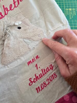 feine Ziernähte nachträgtlich auf den zerrissenen Stickbildern und Stoffstücken der Schultütenkissen
